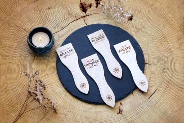 Lot de spatules à raclette en bois personnalisées avec gravure de prénoms et phrases humoristiques.