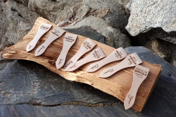 Lot de spatules à raclette en bois personnalisées avec gravure de prénoms et phrases humoristiques.