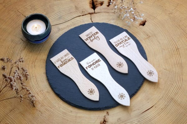 Lot de spatules à raclette en bois personnalisées avec gravure de prénoms et phrases humoristiques.