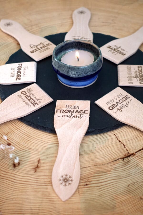 Lot de spatules à raclette en bois personnalisées avec gravure de prénoms et phrases humoristiques.