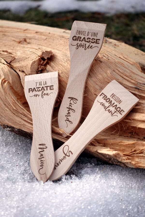 Lot de spatules à raclette en bois personnalisées avec gravure de prénoms et phrases humoristiques.
