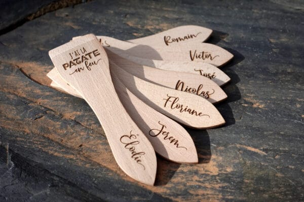 Lot de spatules à raclette en bois personnalisées avec gravure de prénoms et phrases humoristiques.