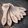 Lot de spatules à raclette en bois personnalisées avec gravure de prénoms et phrases humoristiques.